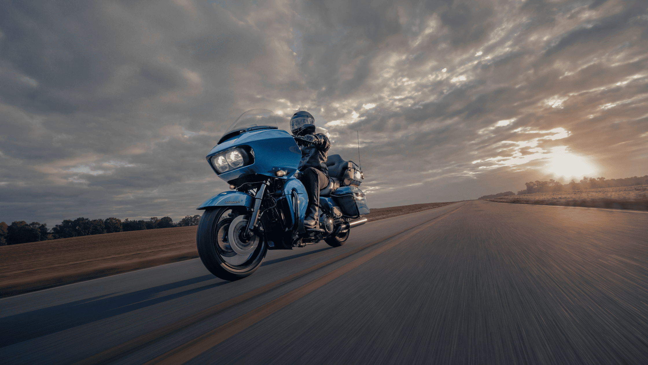  A rider on a blue motorcycle travels along a scenic road near Mount Juliet, TN, showcasing the 2024 Harley-Davidson® Road Glide® Limited.