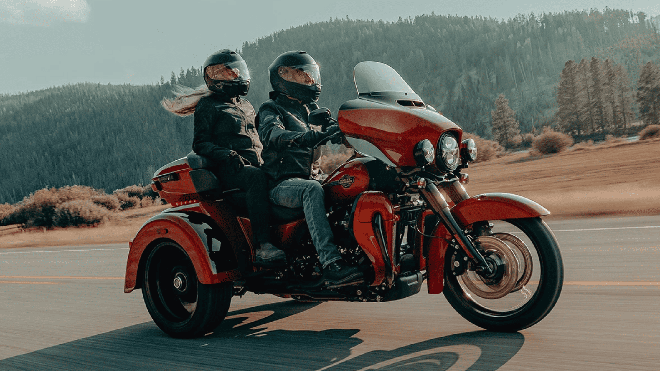 Two riders cruising on a 2025 Harley-Davidson Tri Glide Ultra through wooded hills near Mount Pleasant, TN